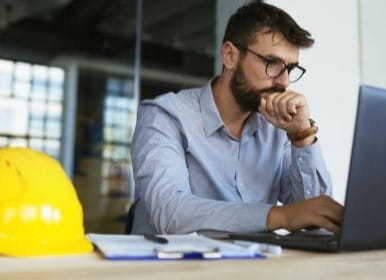 Engineer designing a heat trace system on a laptop next to a hard hat