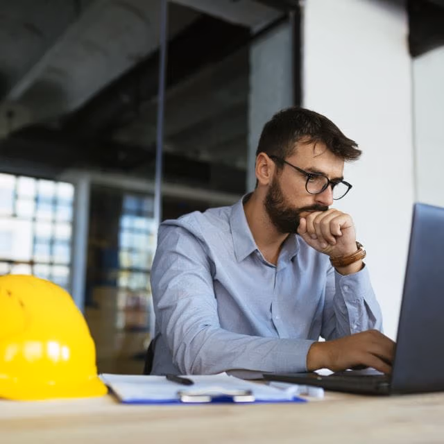 Engineer designing a heat trace system on a laptop next to a hard hat