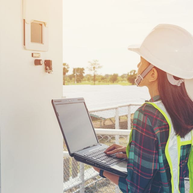 Picture of an engineer on a laptop looking at a machine