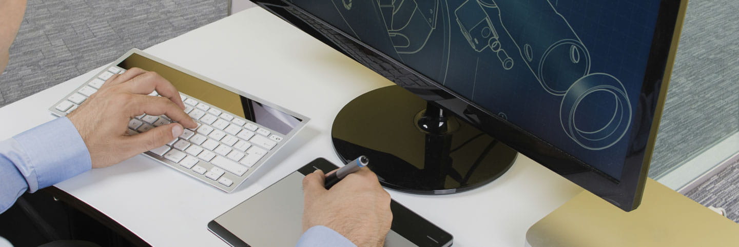 Person at computer looking at CAD drawing and making notes