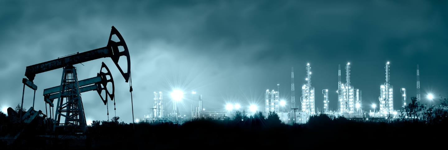 photo of a oil field with a processing plant in the background